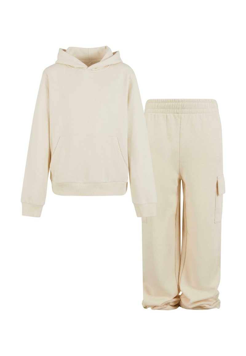 Ljusbeige huvtröja med en framficka, tillsammans med matchande sweatpants med en sidoficka, båda i mjukt tyg.