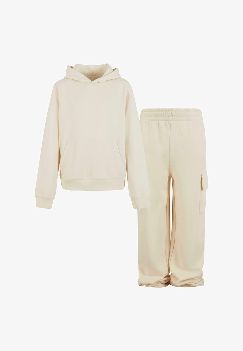 Felpa con cappuccio beige chiaro con tasca frontale abbinata a pantaloni tuta con tasca cargo laterale, entrambi in tessuto morbido.