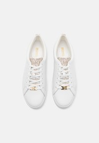 Weiße Ledersneaker mit strukturierten, beigen Textilakzenten, flachen Schnürsenkeln und einem goldenen Logodetail an der Seite.