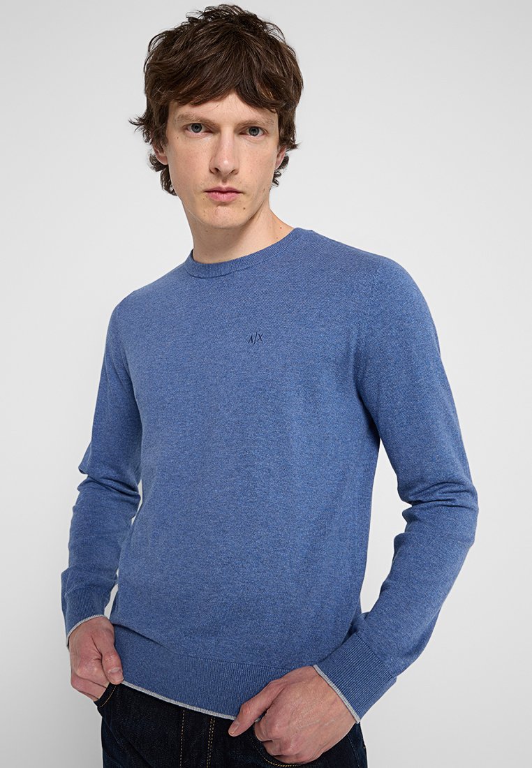 Hellblauer Rundhals-Pullover mit langen Ärmeln, aus strukturiertem Strickstoff. Verfügt über ein dezentes Logo auf der Brust und gerippte Bündchen.