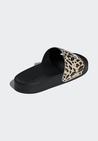 Czarna klapka na płaskim obcasie z szerokim paskiem w zwierzęcy wzór w beżowe i brązowe plamki. Podeszwa wewnętrzna o fakturze oraz gładka czarna zewnętrzna podeszwa.