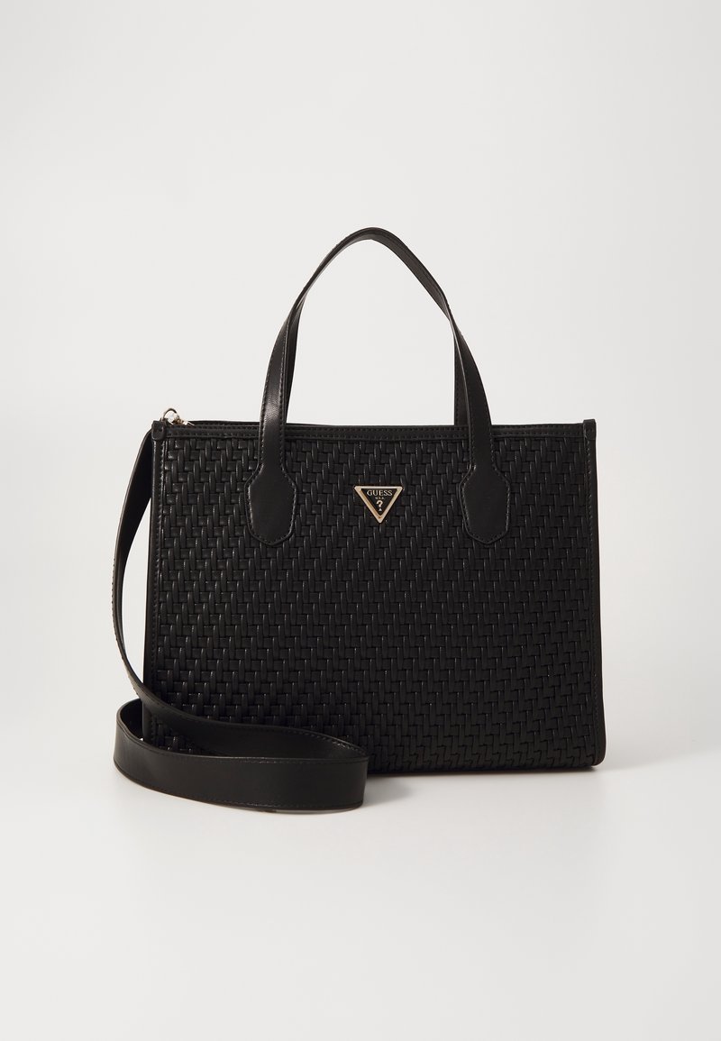 Sac à main en cuir noir tissé avec deux poignées, une longue bandoulière et un logo triangulaire doré Guess à l'avant.