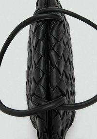 Borsa a mano in pelle intrecciata nera con texture liscia, caratterizzata da una forma arrotondata e due manici lunghi e curvi.