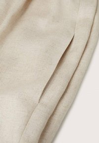 Tissu beige clair avec une surface douce et texturée et des plis subtils. Le matériau semble être du lin, présentant un tissage simple et naturel.