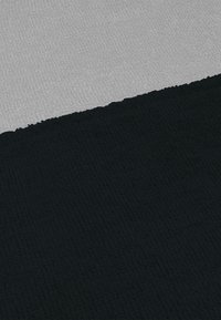 Schwarz-grauer Textilstoff mit strukturierter Oberfläche, der aus zwei Hälften besteht: einer tiefschwarzen und einer hellgrauen, jeweils mit unterschiedlichen Texturen.