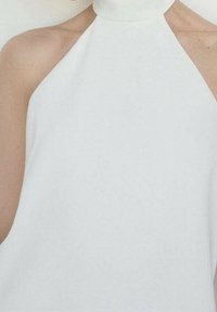 Top blanc à col halter, en tissu lisse, design minimaliste, structure ajustée avec un col haut, mettant en valeur les épaules nues.