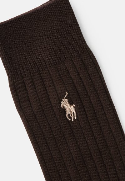 Brune ribbede sokker med en tekstureret strik, der har et lille broderet logo af en hest og rytter i lys beige nær kanten.