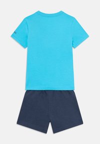Lysblå bomulds t-shirt med korte ærmer og rund hals, parret med marineblå bomulds shorts med elastisk talje.