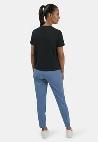 Black t-shirt with short sleeves, paired with light blue tapered pants. The outfit features a simple design with a smooth texture and athletic fit.