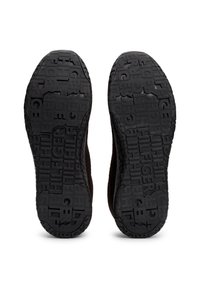 Semelles de chaussures foncées avec une semelle texturée comportant le mot répété "HILFIGER" en différentes tailles et orientations.