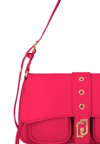 Bolso sintético de color rosa brillante con cierre de solapa, acentos en hardware dorado y correa ajustable. Presenta botones decorativos y detalle del logo.