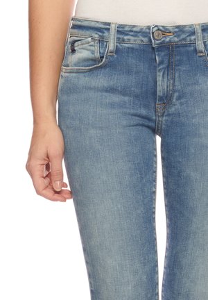Helleblaue Denim-Jeans mit glatter Textur, ausgestattet mit fünf Taschen, einem Knopf- und Reißverschluss sowie subtiler Verblassung im Oberschenkelbereich.