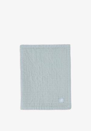 Couverture en coton bleu clair avec une surface texturée, présentant un motif subtil et une petite étiquette de marque dans le coin inférieur droit.