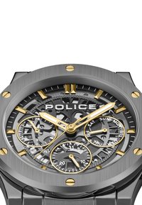 Orologio in acciaio inossidabile grigio con dettagli dorati, dotato di quadrante scheletrato, tre sottogiri e un design audace delle lancette delle ore e dei minuti.