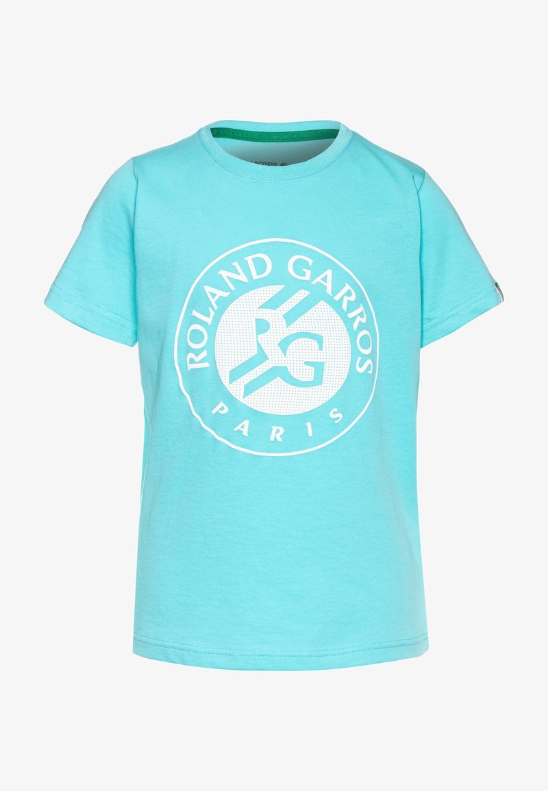 Vaaleansininen puuvillapaitapusero, jossa on lyhyet hihat, pyöreä kaula-aukko ja painettu pyöreä logo, jossa lukee "ROLAND GARROS" ja "PARIISI" valkoisella.