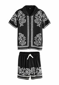 Čierny dvojdielny outfit pozostávajúci z košele s krátkym rukávom a zodpovedajúcich šortiek. Obe majú biele paisley vzory a kontrastné lemovanie.