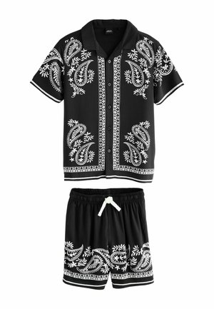 Sort to-delt sæt bestående af en kortærmet skjorte og matchende shorts. Begge har hvide paisley-mønstre og kontrasterende kanter.