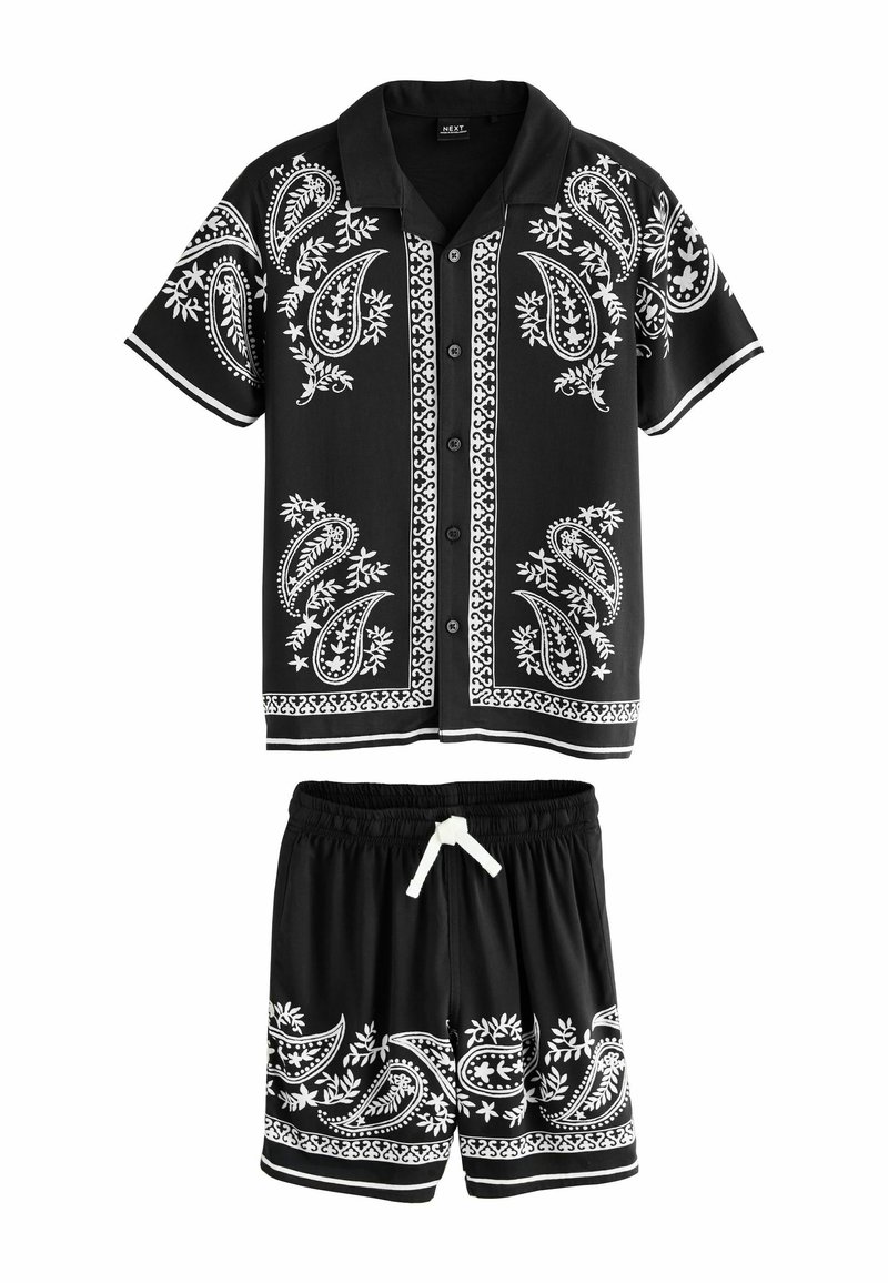 Čierny dvojdielny outfit pozostávajúci z košele s krátkym rukávom a zodpovedajúcich šortiek. Obe majú biele paisley vzory a kontrastné lemovanie.