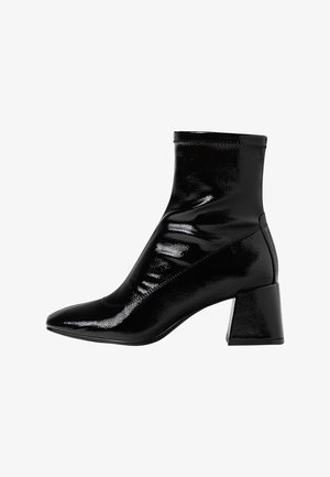 Crni lakirani kožni gležnjača s oštrim nosom, strukturiranim potplatom i jednostavnim dizajnom s mekim nabiranjem na gornjem dijelu.