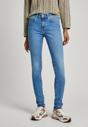 Lyse blå skinny jeans laget av denim, med middels høy midje, fem lommer og subtil falming. Kombinert med sneakers i blandede materialer.