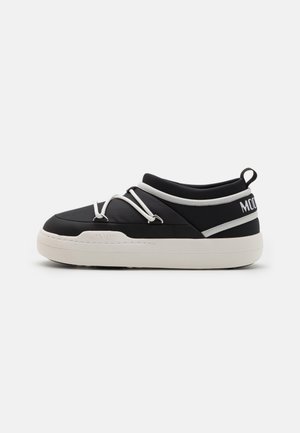 Baskets slip-on noires avec une semelle blanche épaisse, des lacets élastiques blancs croisés sur le dessus et le texte "MOON BOOT" sur le talon et la semelle.