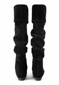 Bottes noires en suède, au-dessus du genou, avec un design amolli. Elles possèdent des talons plats et une texture plissée le long de la tige. Finition lisse, aspect doux.