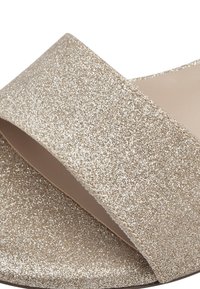 Glittrande guldsandaler i en bred, texturerad rem med en mjuk foder, med rund tå och öppen baksidesdesign.