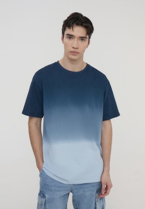 T-shirt a maniche corte con una sfumatura che va dal blu scuro in alto al blu chiaro in basso, realizzato in morbido cotone.