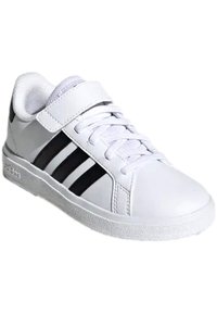 Zapatilla deportiva blanca hecha de material sintético, con acentos de rayas negras, una correa de velcro y una suela de goma texturizada.