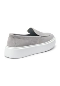 Scarpa slip-on in suede grigia con suola in gomma bianca, caratterizzata da una finitura liscia e dettagli di cucitura minimali sul tallone e sulla parte superiore.
