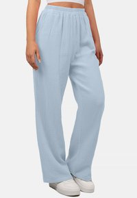Lichtblauwe, lichte, getextureerde wijde broek met een elastische tailleband, gedragen met witte sneakers, met een relaxte pasvorm.