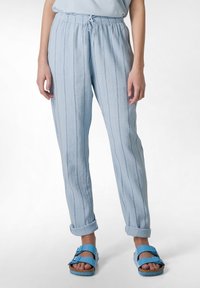 Ljust blå, lätta, randiga byxor med elastisk midja. Uppvikta fållar och slät textur. Bärs med blå sandaler.