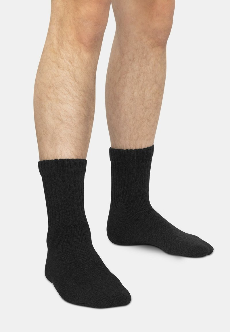 Schwarze gerippte Socken mit weicher Textur, die bis zur Mitte der Wade reichen, mit einem glatten Strickdesign und einem engen Sitz am Knöchel.
