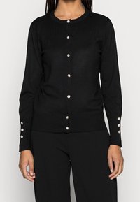 Black cardigan made of ribbed knit fabric, featuring a round neckline and decorative pearl-like buttons along the front and cuffs.