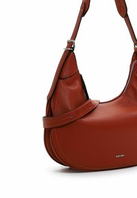 Red leather shoulder bag with a textured finish, curved design, silver hardware, and an adjustable strap featuring embossed branding.