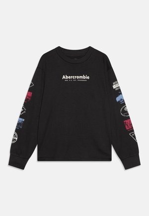 Chemise noire à manches longues avec le texte "Abercrombie" sur la poitrine et des patchs graphiques multicolores sur les deux manches.