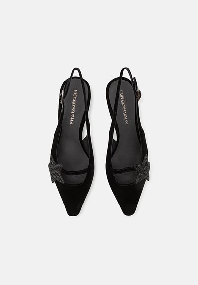 Black velvet slingback heels with pointed toes, featuring a star-shaped accent on the side and a smooth, shiny inner lining.