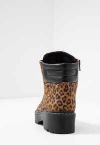 Stivale alla caviglia in stampa leopardata con esterno in suede marrone, accento in pelle nera sul tallone e chiusura con zip, dotato di suola in gomma testurizzata.