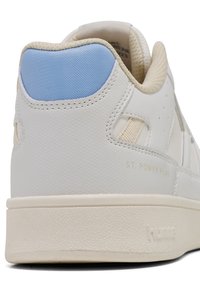 Białe sneakersy, teksturowane wykończenie, jasnoniebieski akcent na pięcie, beżowe detale, gumowa podeszwa z delikatną teksturą, wytłoczone logo i nazwa modelu.