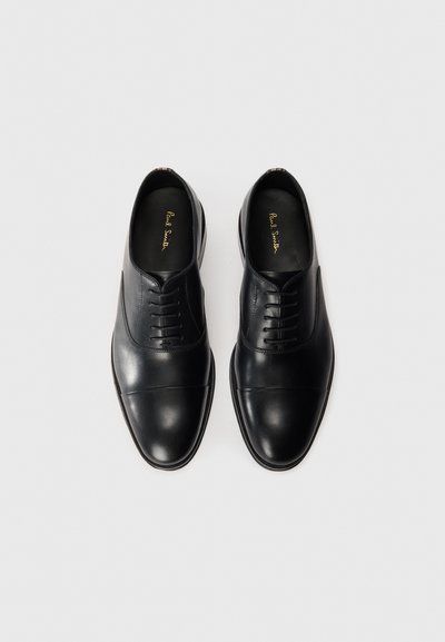 Scarpe eleganti in pelle nera con finitura liscia, caratterizzate da un design con lacci, punta arrotondata e sottili dettagli di cucitura. Suole piatte.