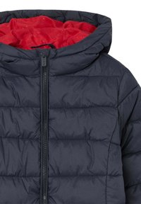 Giacca puffer trapuntata blu navy con cerniera frontale e cappuccio foderato in tessuto rosso brillante.