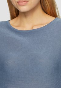 Hellblaues Stricktop mit rundem Ausschnitt. Die Textur ist gerippt und der Stoff wirkt weich und atmungsaktiv.