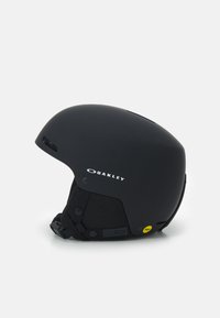 Czarny kask narciarski o gładkiej matowej powierzchni, zaokrąglonym kształcie, regulowanym pasku pod brodą oraz otworach wentylacyjnych, z logo Oakley.