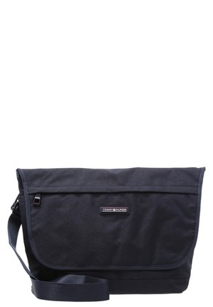 Sac messager noir Tommy Hilfiger avec bandoulière réglable et fermeture à rabat avant.