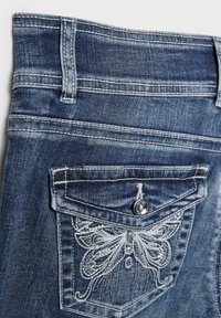 Jeans aus Denim mit einem Schmetterlingsstickereimotiv auf der hinteren Tasche, ausgestattet mit einem Knopf und metallischen Akzenten. Dunkelblaue Waschung mit strukturierter Stoffoberfläche.