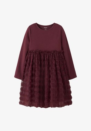 Burgunderfarbenes Kleid mit langen Ärmeln, das ein strukturiertes Oberteil und einen mehrlagigen Tüllrock mit Rosettenmustern hat. Weicher Stoff.