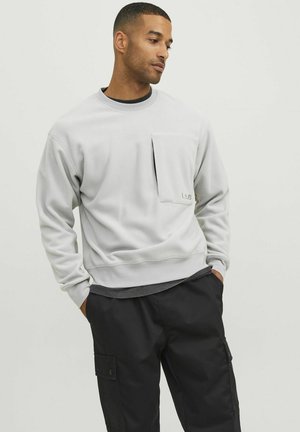 Lysegrå sweatshirt lavet af blødt stof, med en frontlomme, rund halsudskæring og ribbede manchetter, parret med sorte cargo-bukser.