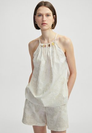 Haut en lin blanc à bretelles avec des plis et des accents de perles multicolores au niveau du col, accompagné de shorts assortis au motif floral subtil.