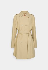 Trench-coat beige avec fermeture boutonnée croisée, épaulettes et ceinture assortie. Lignes épurées et tissu texturé.