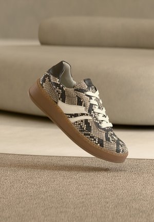 Scarpa da ginnastica con motivo a pelle di serpente sintetica marrone testurizzata, con dettagli bianchi e lacci, e suola in gomma. Design basso con tacco nero.